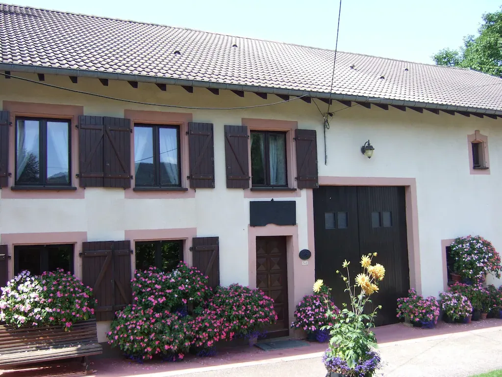 La façade du Gîte Les Fleurs et ses fleurs roses